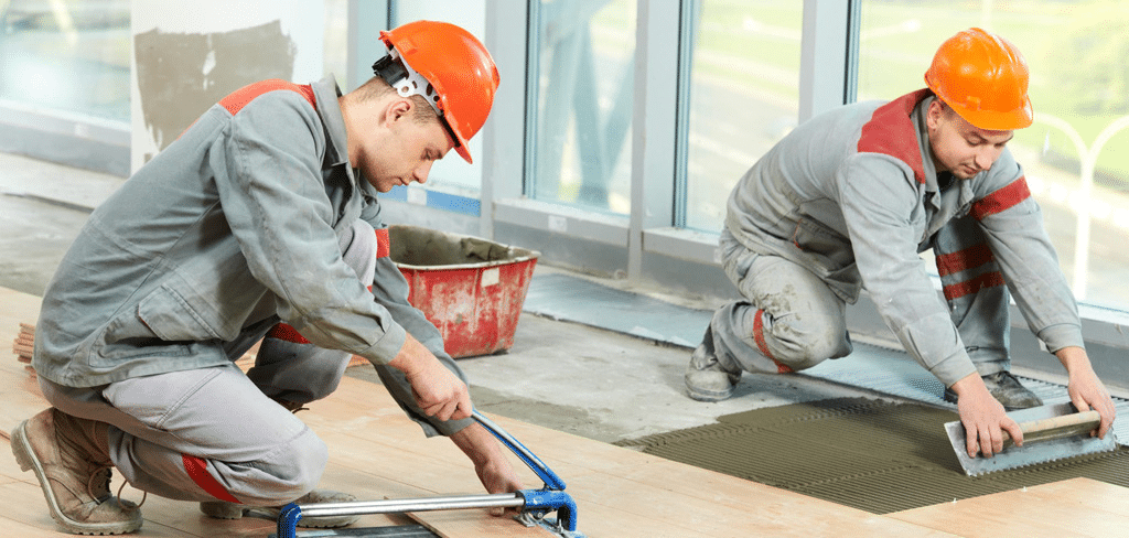 Deux carreleurs posent du carrelage, outils, équipement de sécurité, chantier