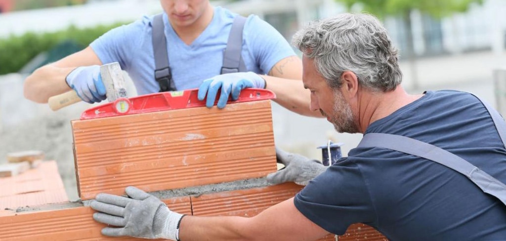 Deux maçons construisent un mur à l'aide d'un niveau à bulle, chantier